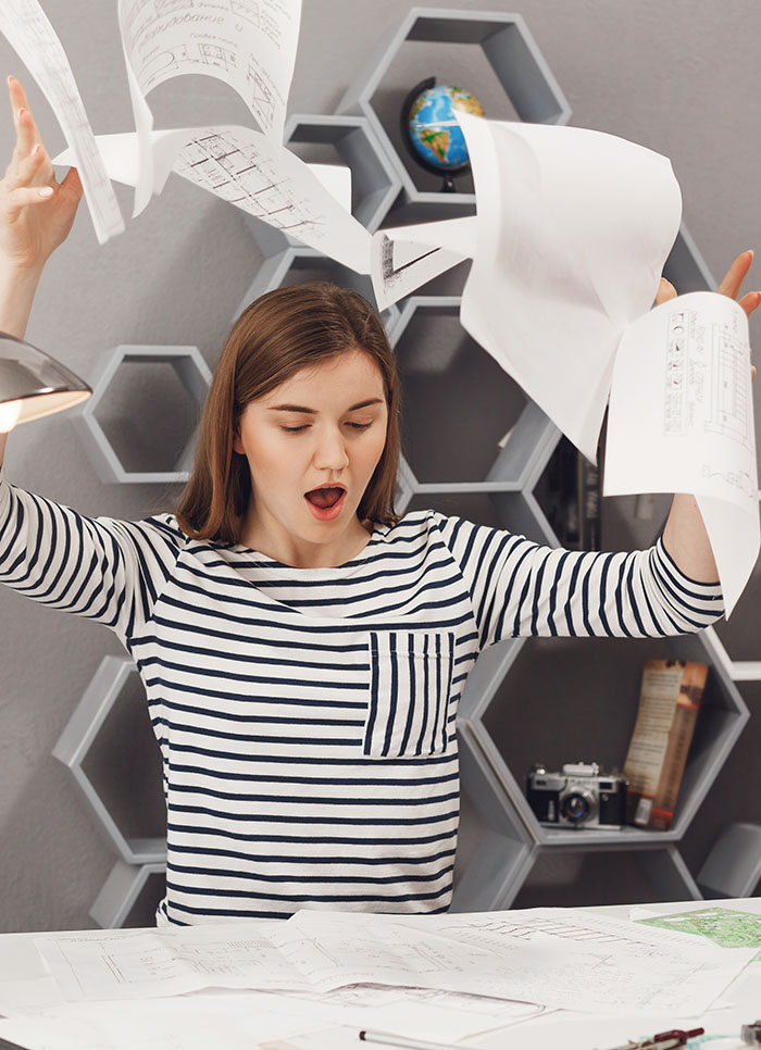 Negative emotions. Portrait of angry young good-looking female architect throwing papers away, being angry with bad result of work after lot of tries.